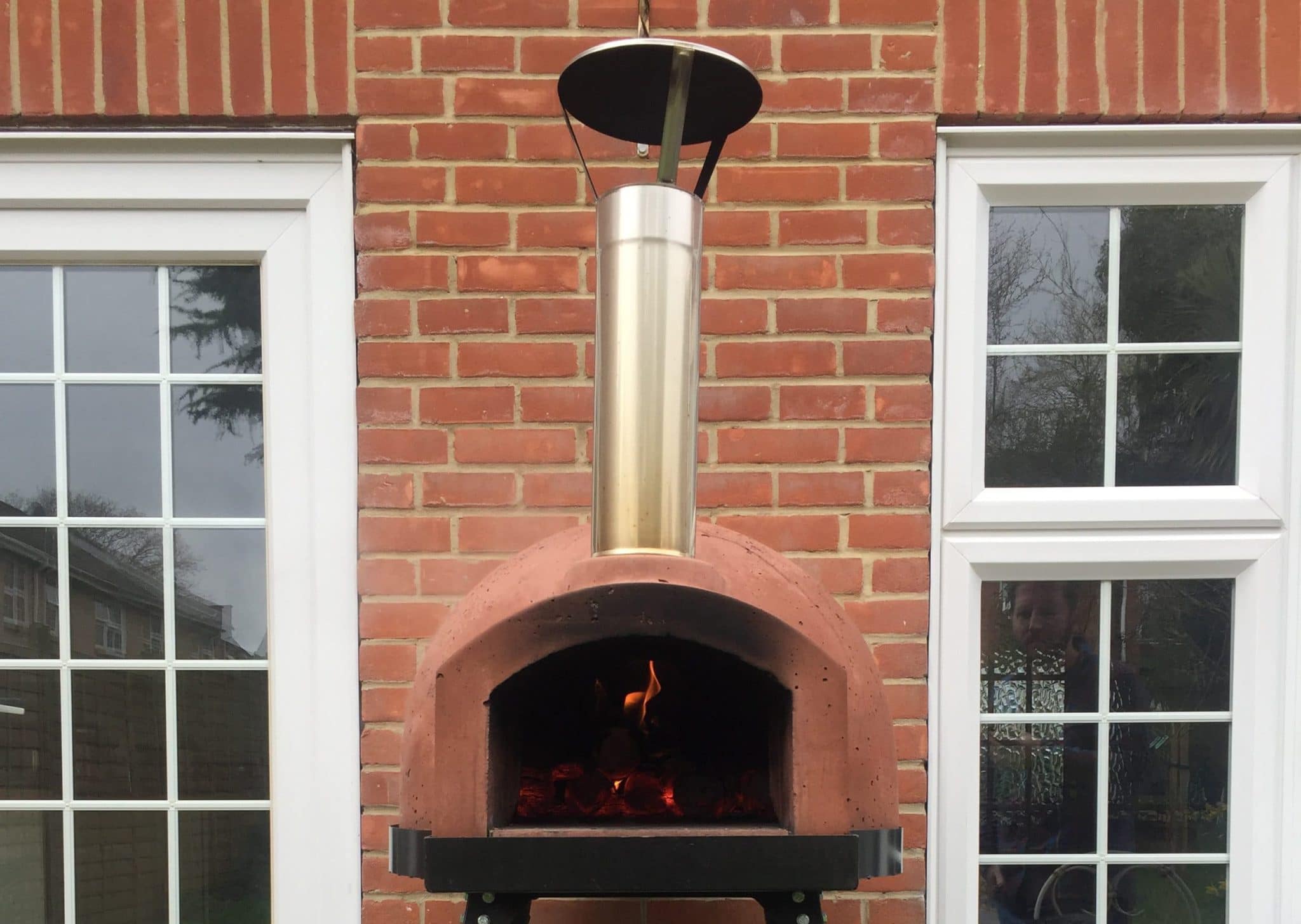 A customer photograph of a lit primo 60 oven on a black oven stand